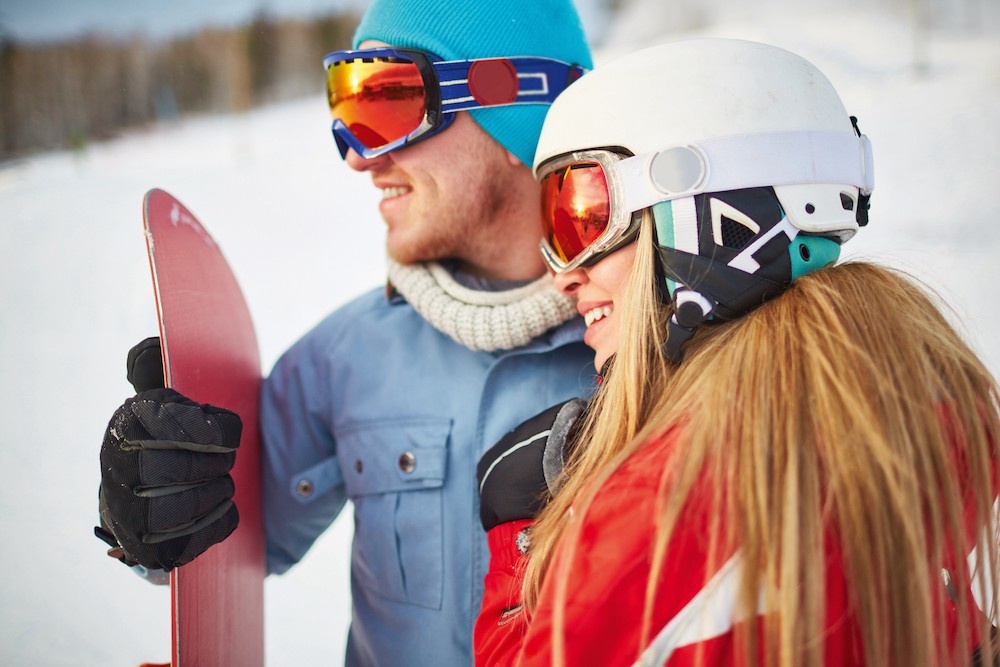 Young female and male snowboarders in winter activewear