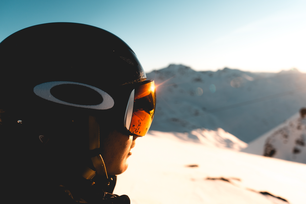 Side profile of a snowboarder wearing Oakley goggles on a snowy mountaintop