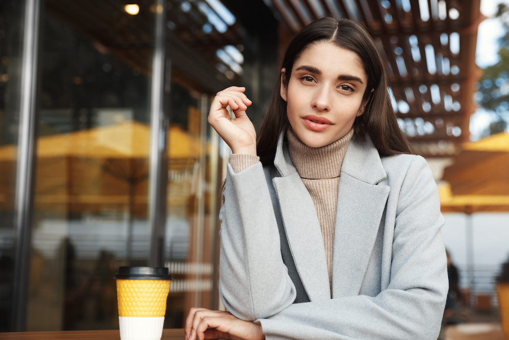 Young stylish woman sitting outside a cafe with coffee